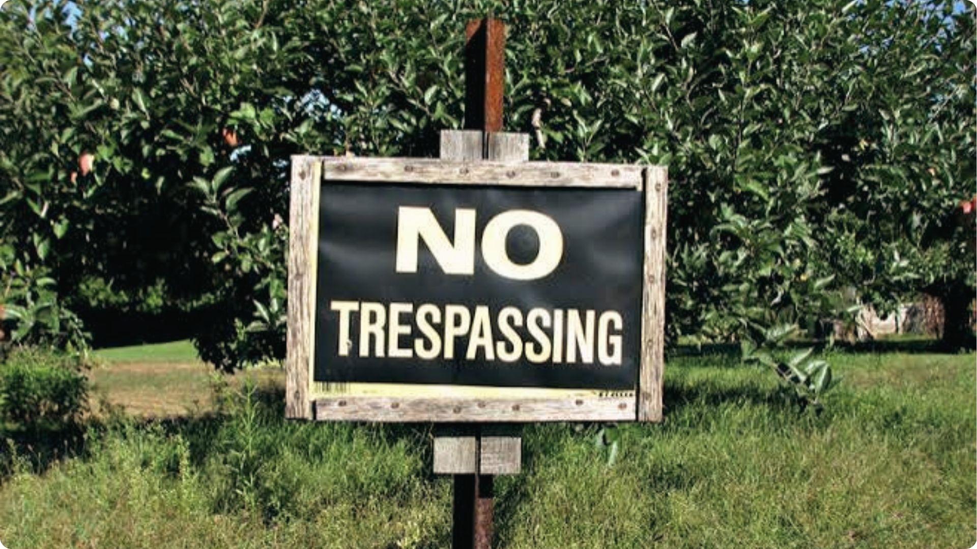 No Trespassing sign in grassy field warning against unauthorized entry for property surveying