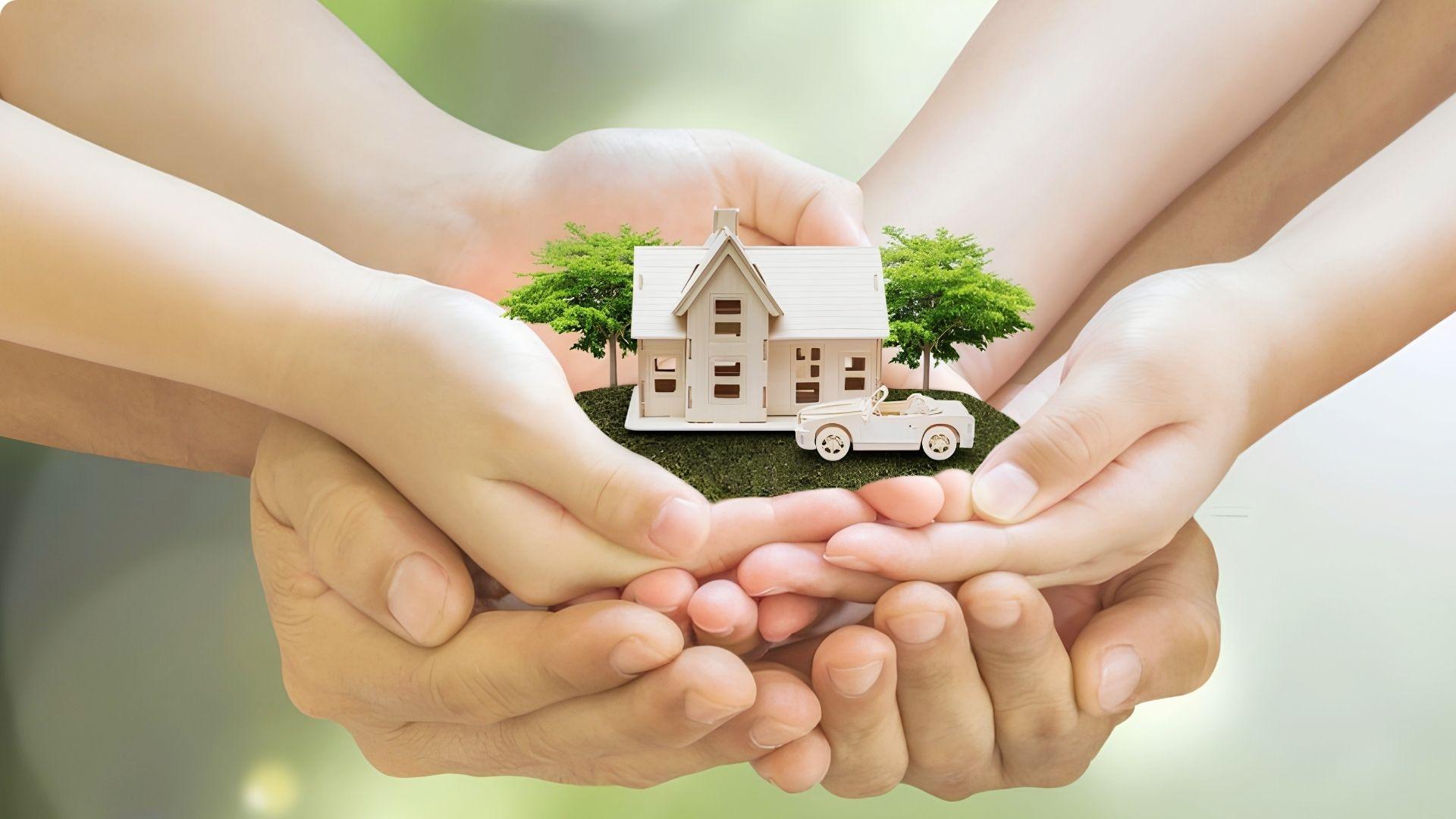 Family hands holding model house with car showing joint family property ownership dream
