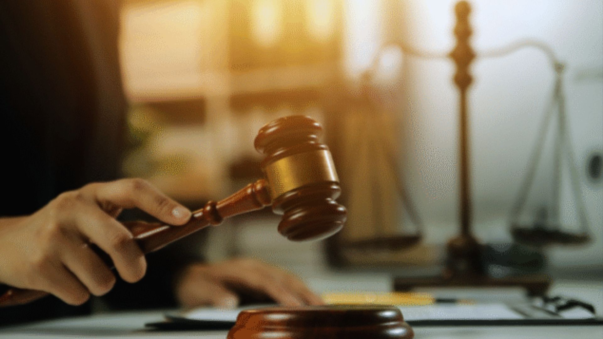 Judge holding wooden gavel with scales of justice in background, courtroom legal auction concept