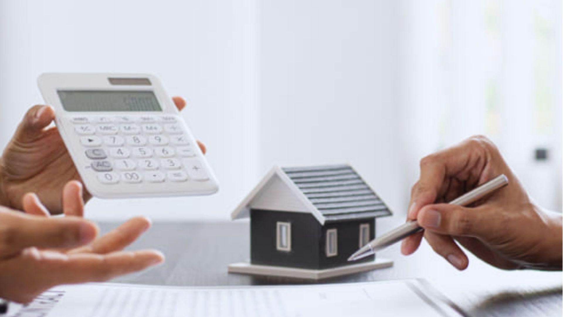 A small black model house on a table with documents.