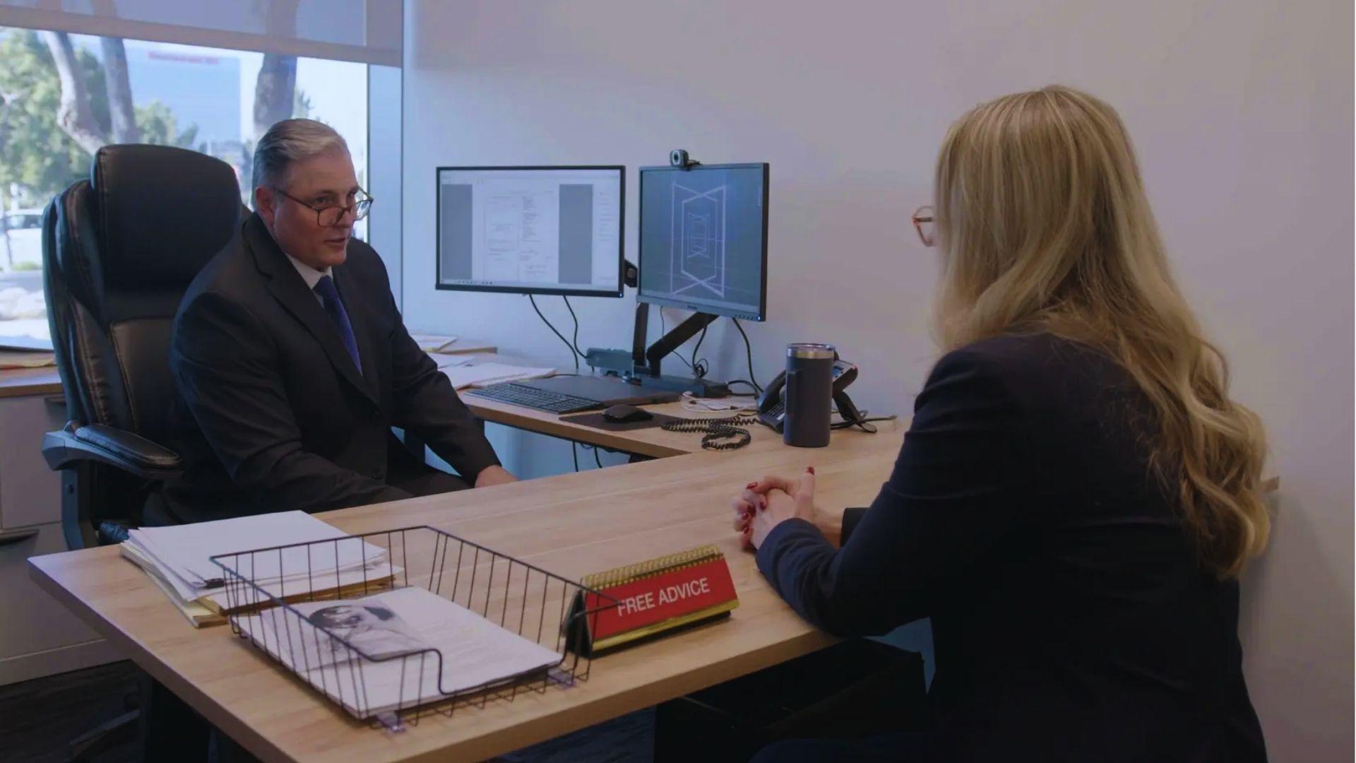 Man in suit at office desk consulting with woman