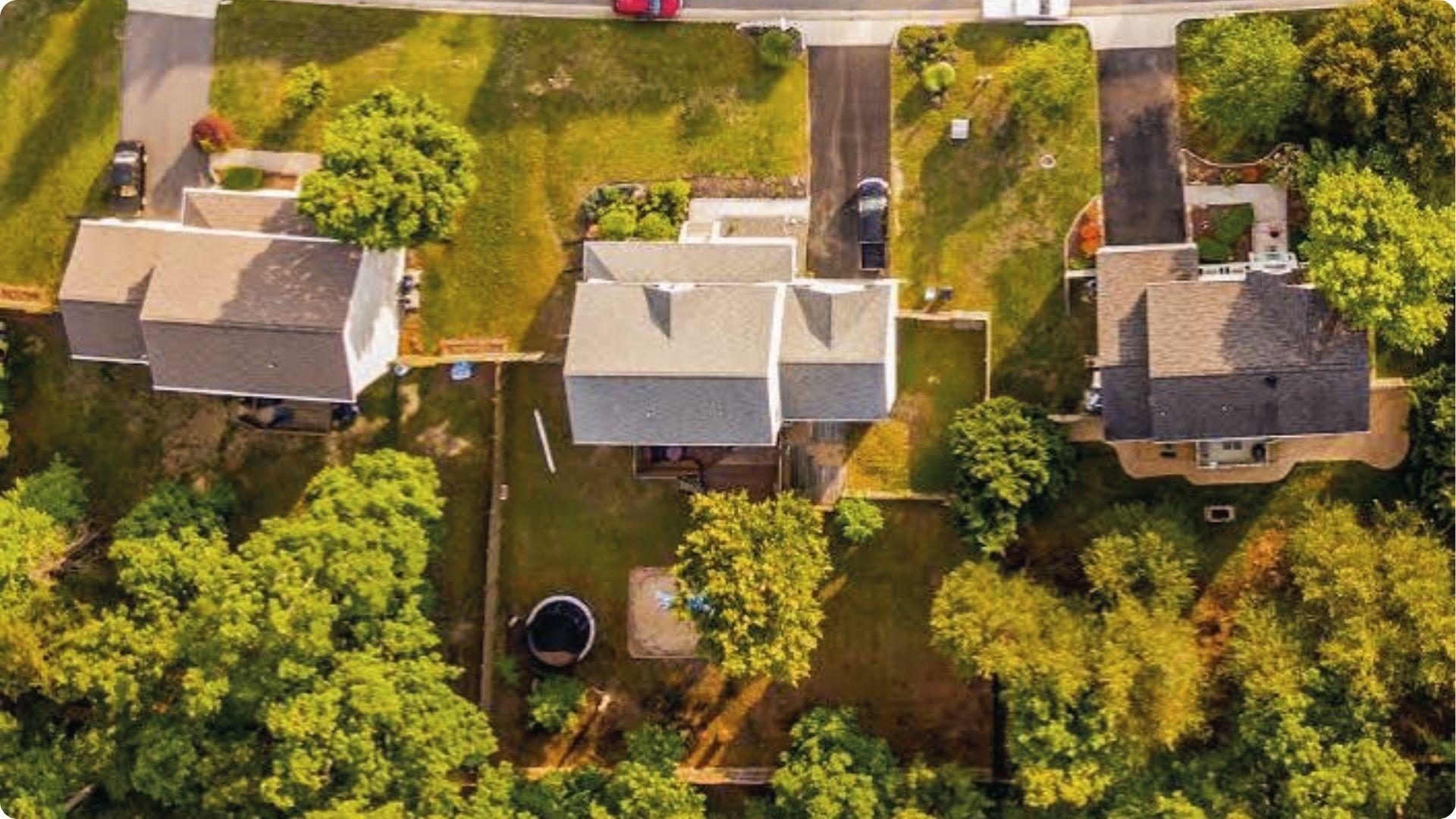 Aerial view of three houses with yards and fences showing property lines easement and encroachment