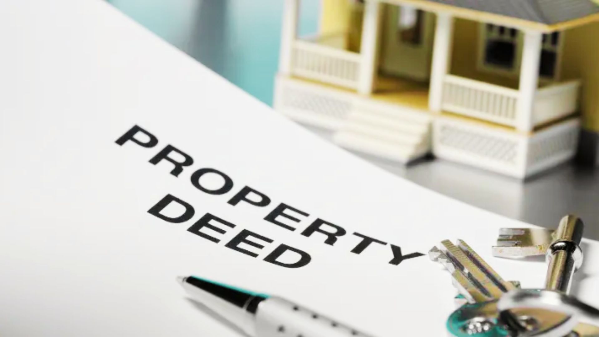 A property deed displayed alongside keys and a house, symbolizing the process of name removal from a deed.