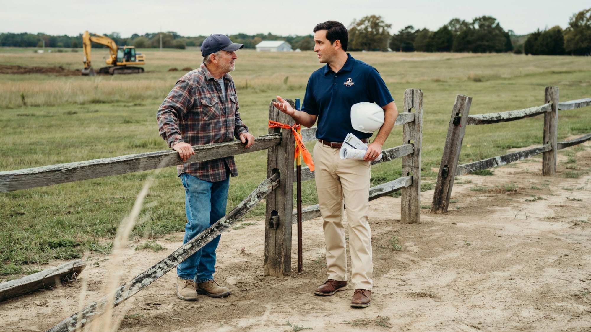 Landowner discussing property access with energy company representative on rural land.