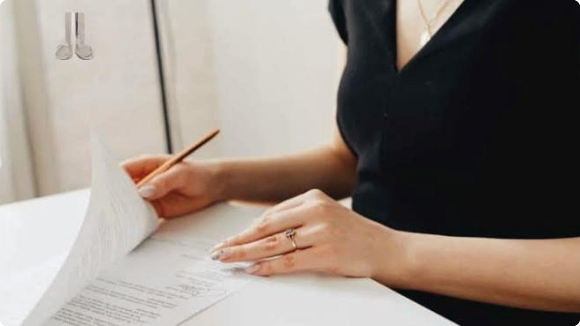 Woman reviewing legal papers with pencil at desk, verifying spousal property petition details.