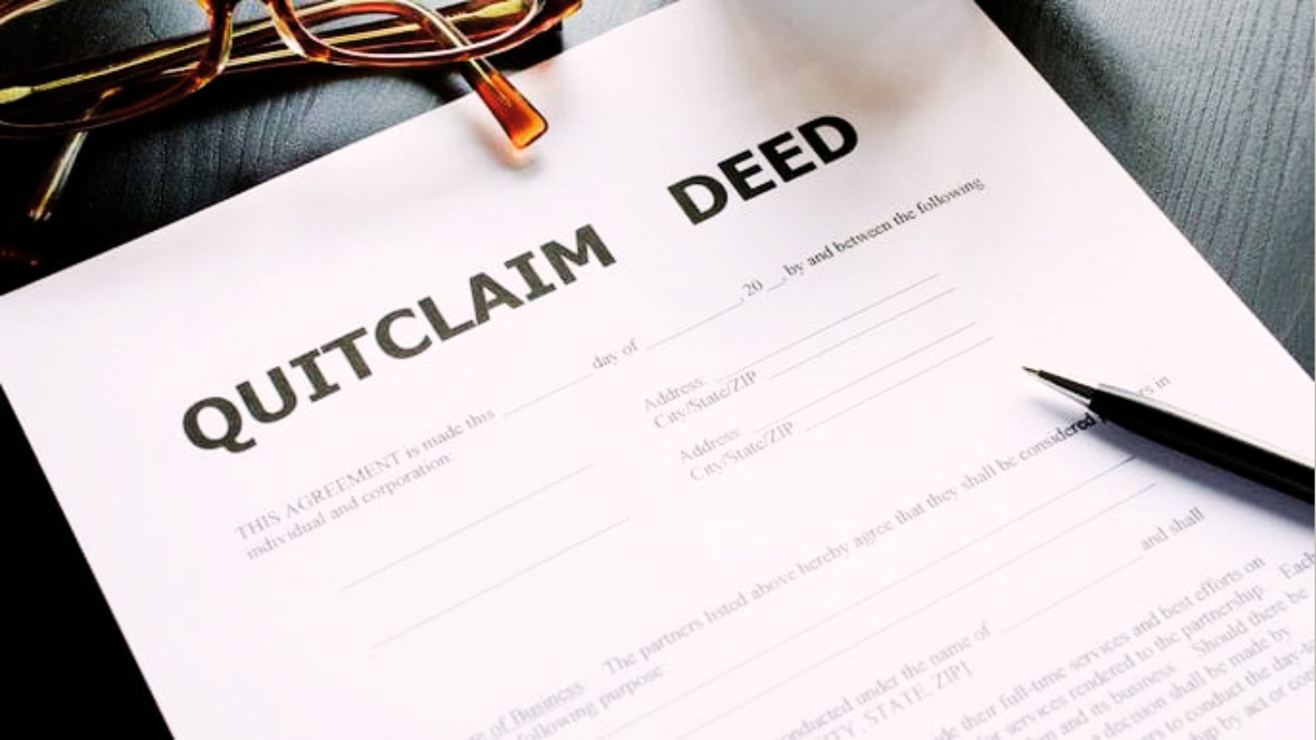 A person reviewing legal documents with a pen, contemplating the process of obtaining a quitclaim deed.