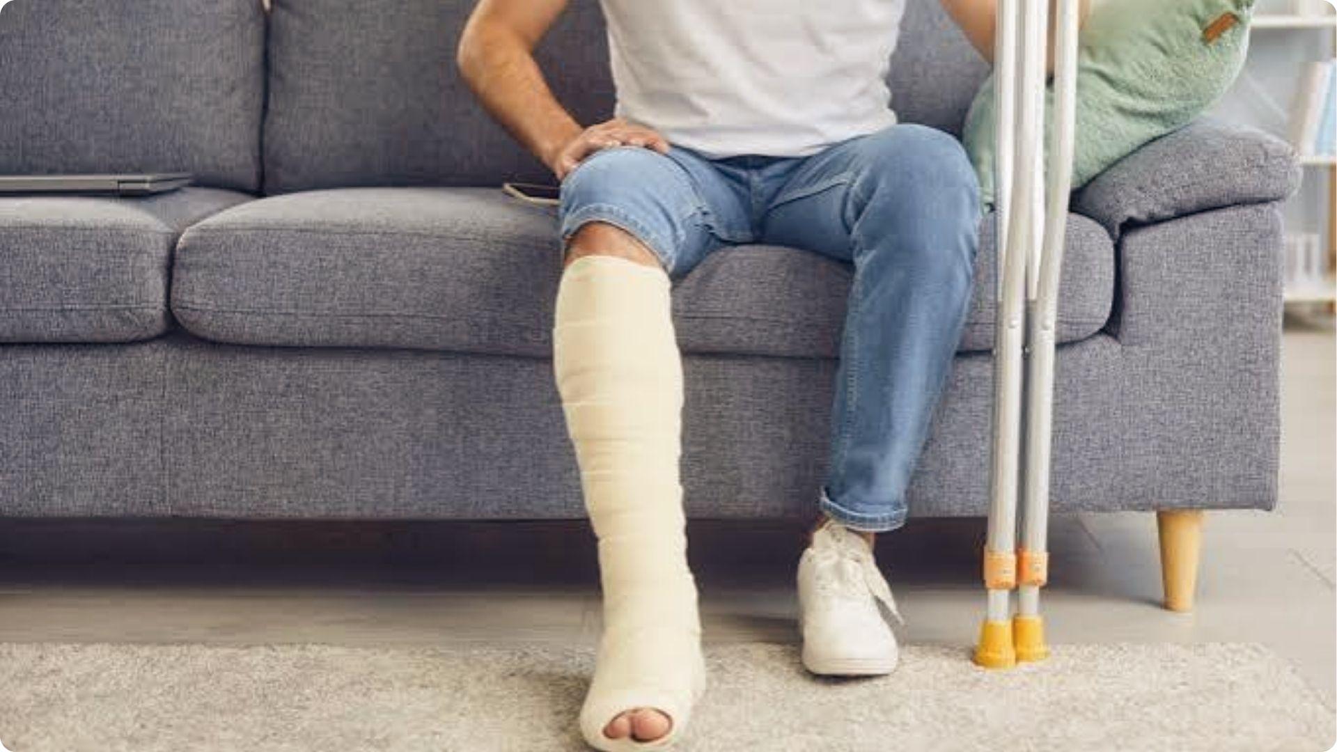 Tenant sitting on sofa with leg in full cast beside crutches after injury on rental property.