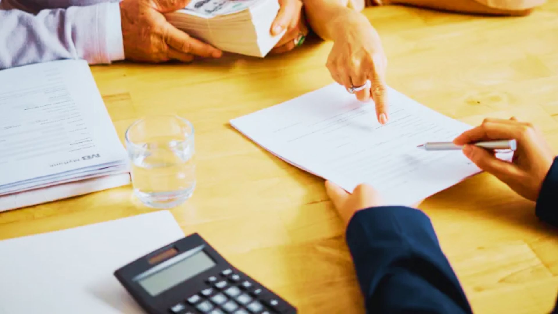 A team of individuals at a table, examining documents and using pens, possibly consulting on a deed removal process.