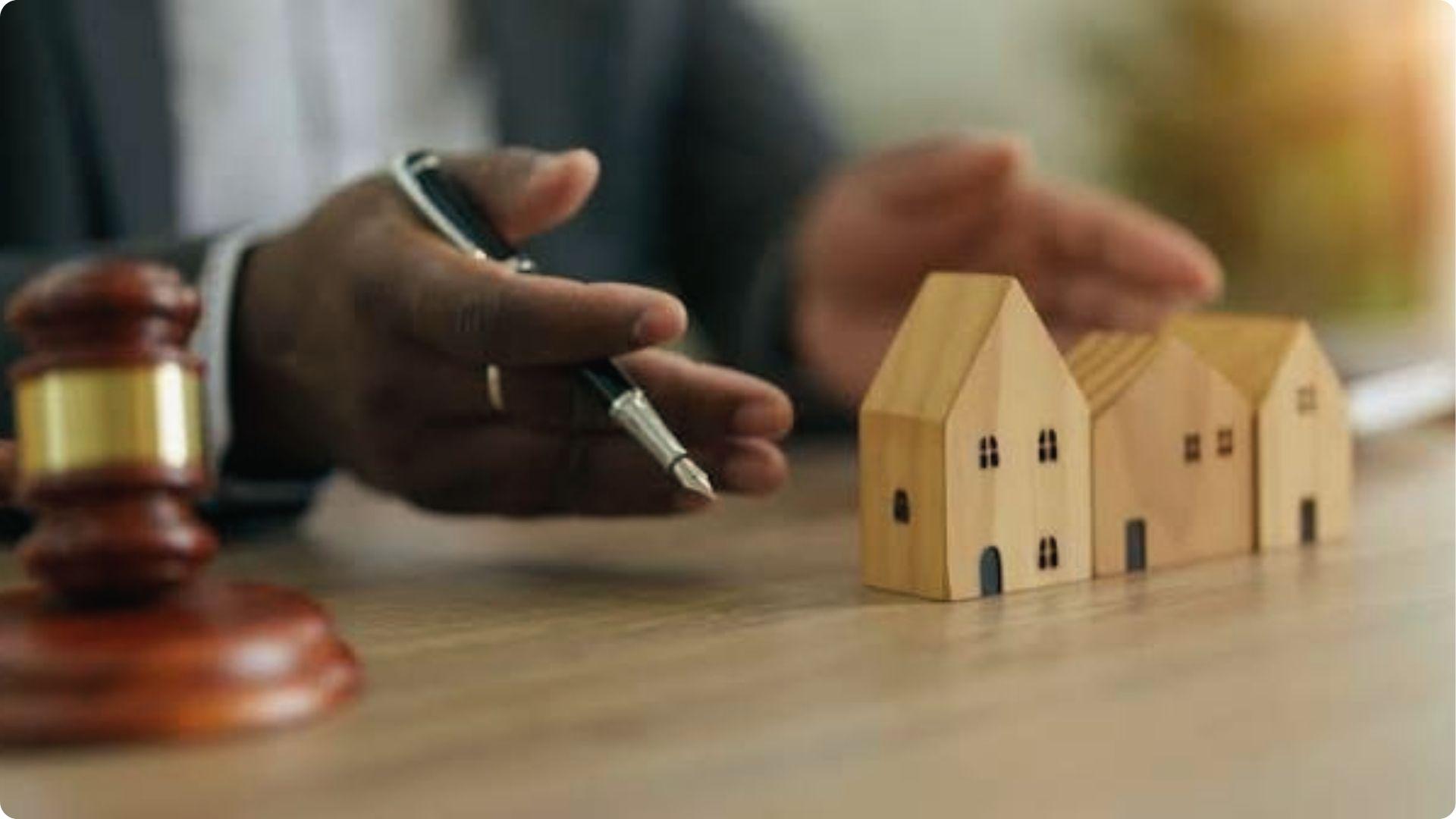 Lawyer with pen and gavel beside wooden houses reviewing property exempt from eminent domain law