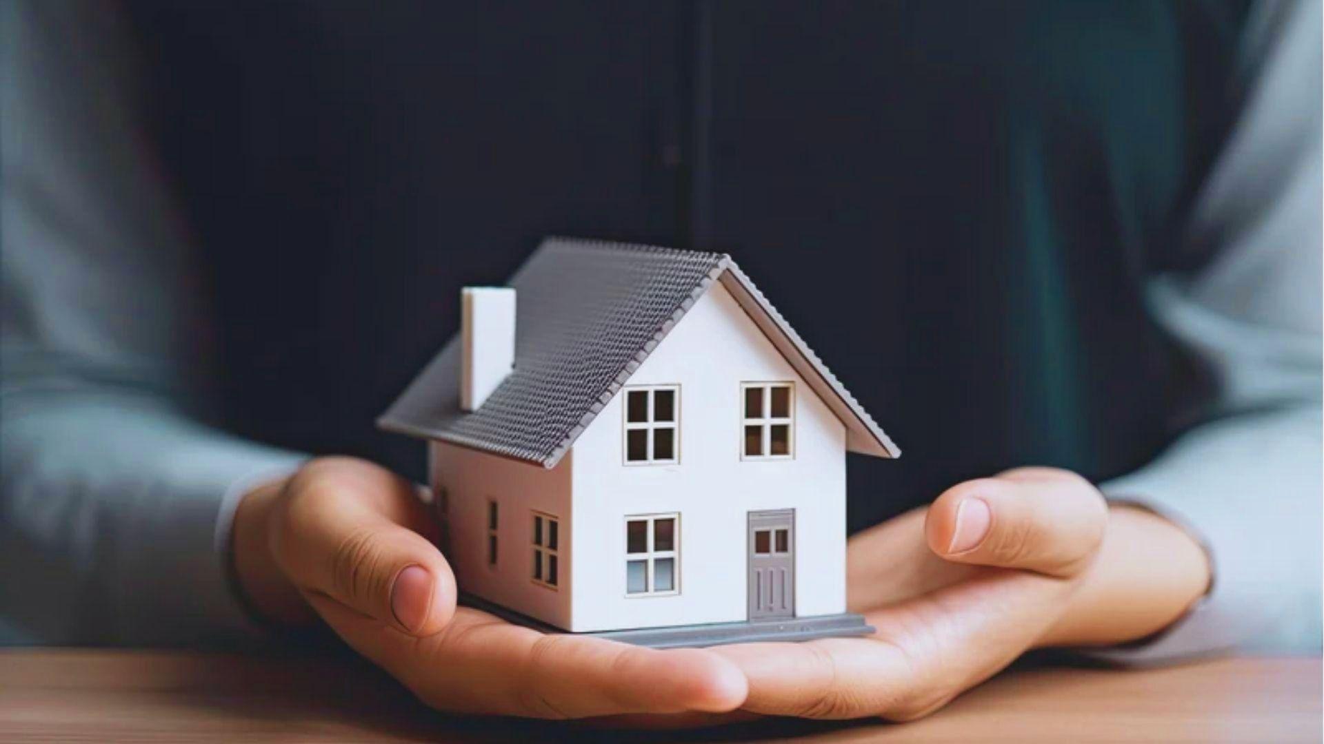 Hands holding small gray model house