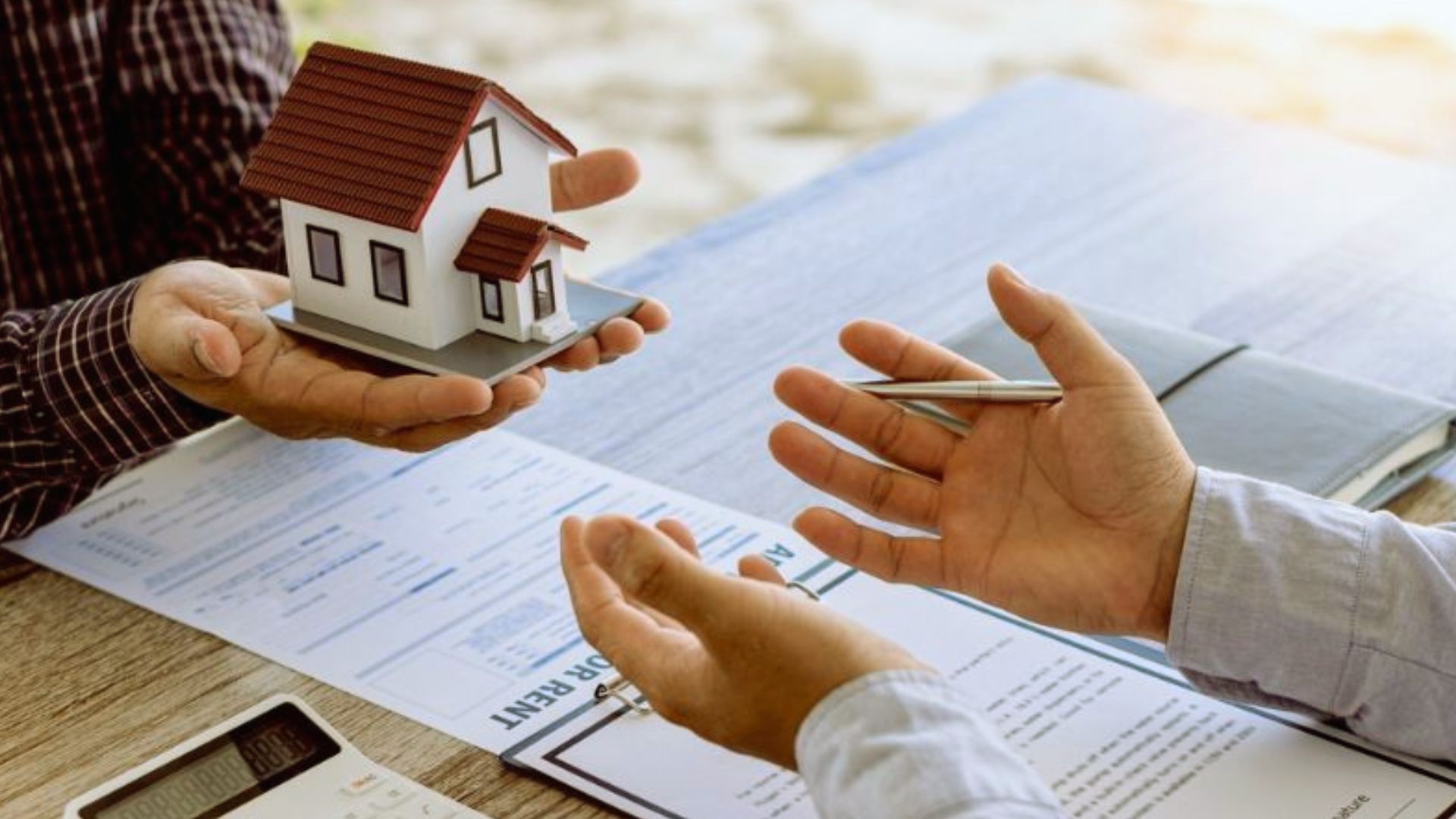 Agent handing model house to buyer during quitclaim deed property transfer agreement signing