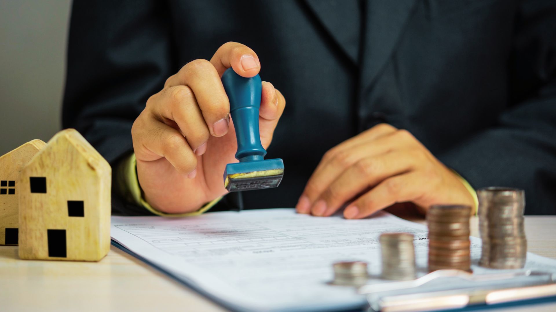 A man in a suit holds a stamp over a document, symbolizing legal processes related to inherited property and taxes.