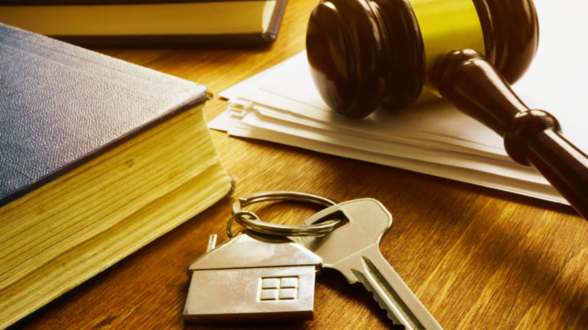 A gavel, house keys, and a contract on a wooden table symbolizing legal property transfer and deed types.