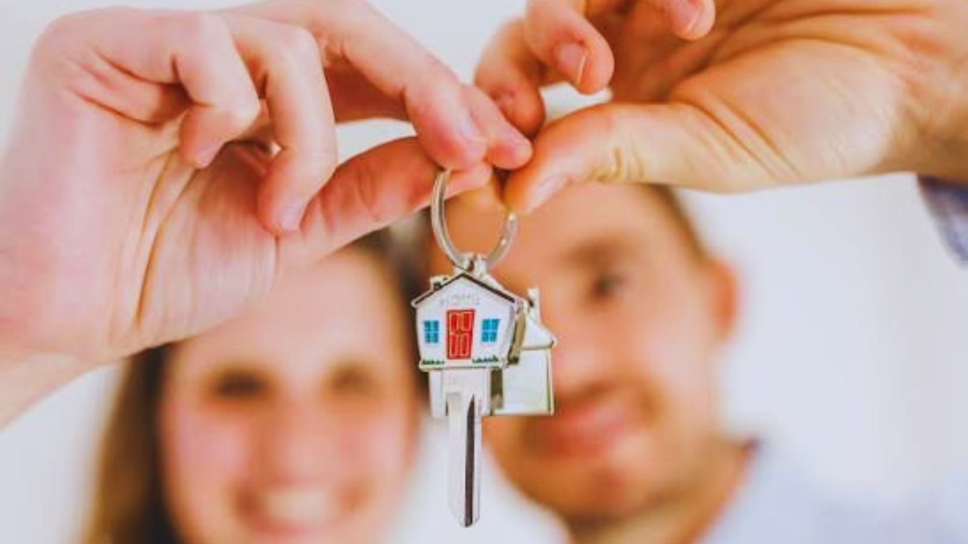 Two individuals holding house keys, symbolizing shared ownership in a community property trust arrangement.
