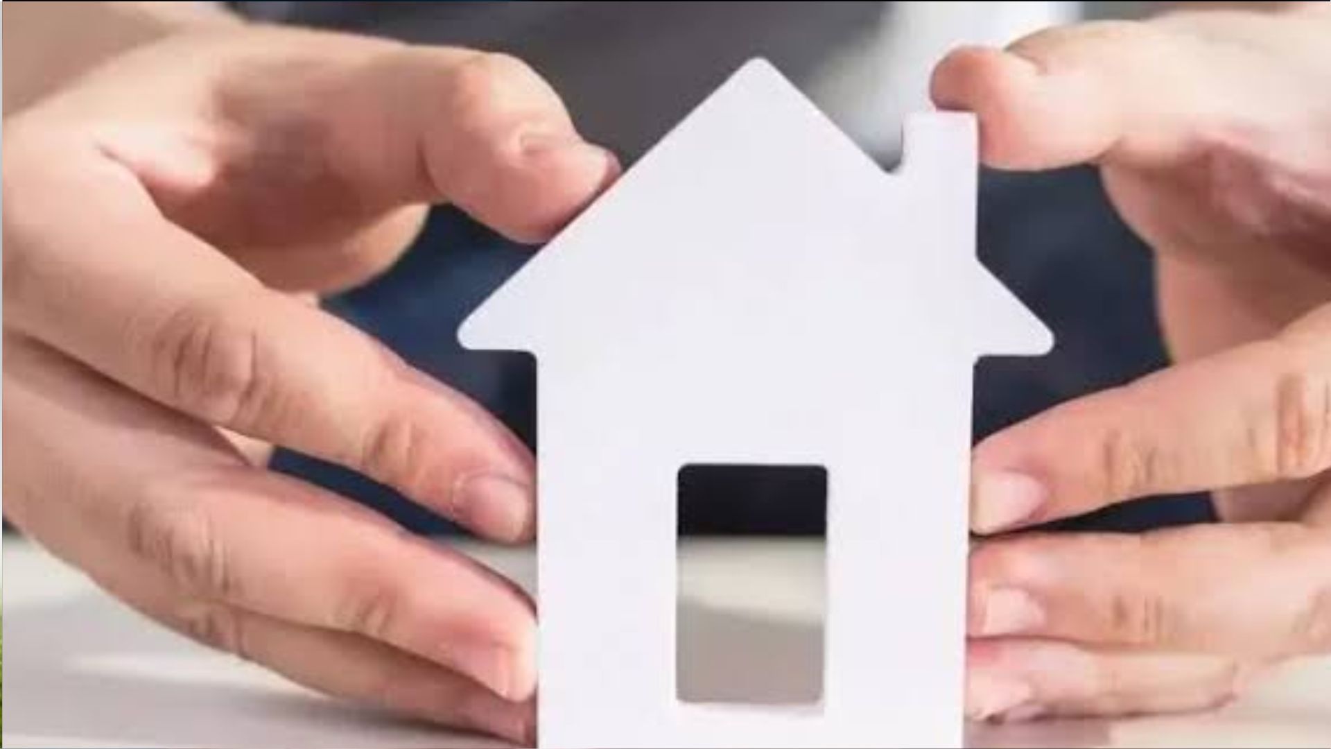 Close-up of hands gently holding white paper house-shaped cutout with small door opening, blurred dark background, home concept.