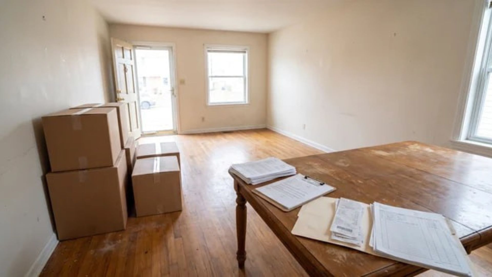 Vacated rental unit with moving boxes and lease documents on a table