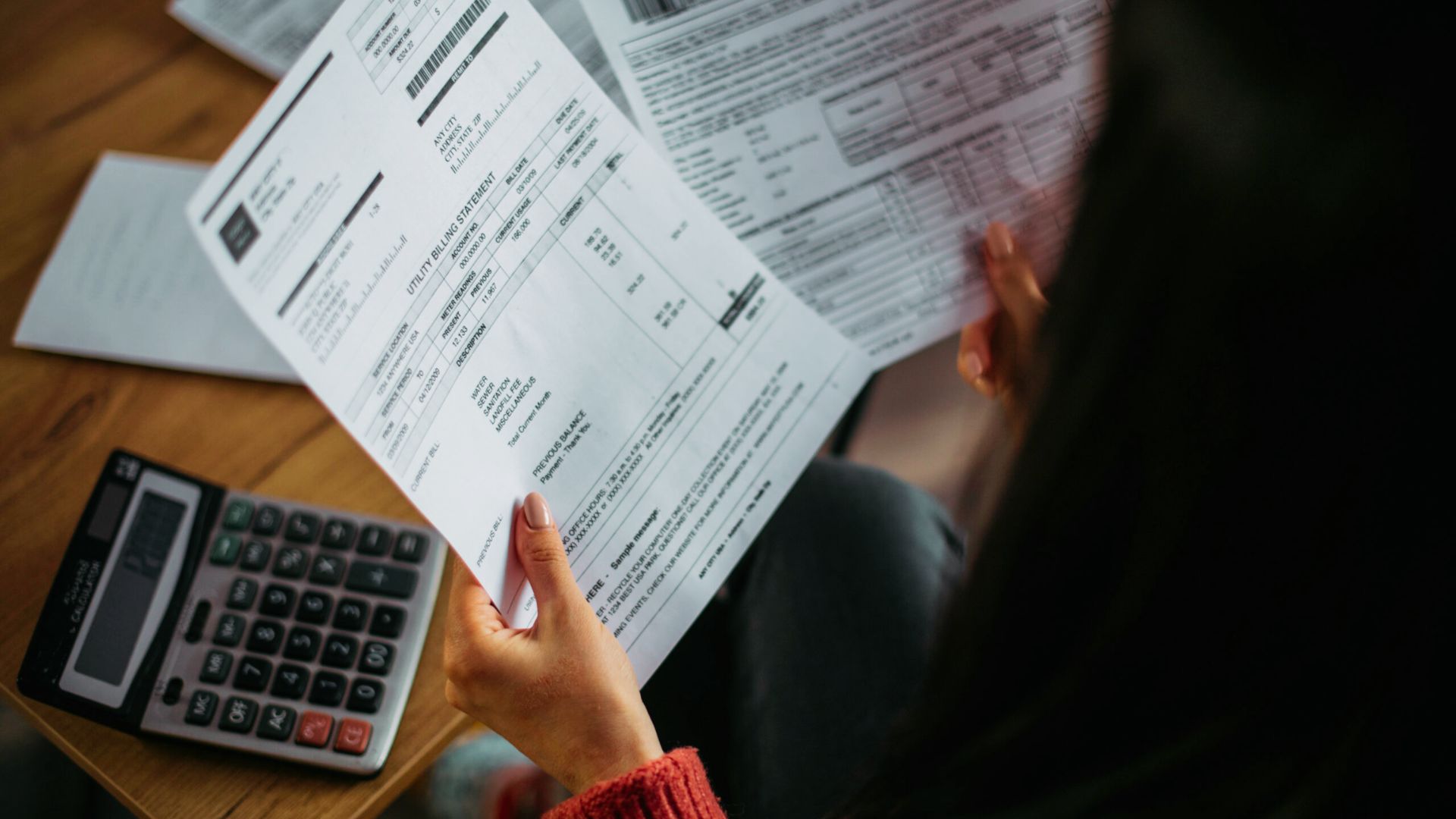 A woman examines tax papers with a calculator, showing consequences of illegal subletting.