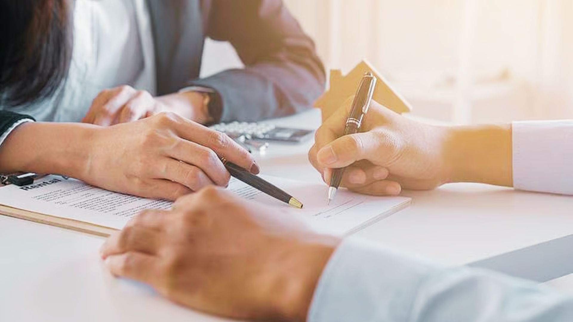 A close-up of two people at a desk, finalizing documents related to illegal subletting agreements.
