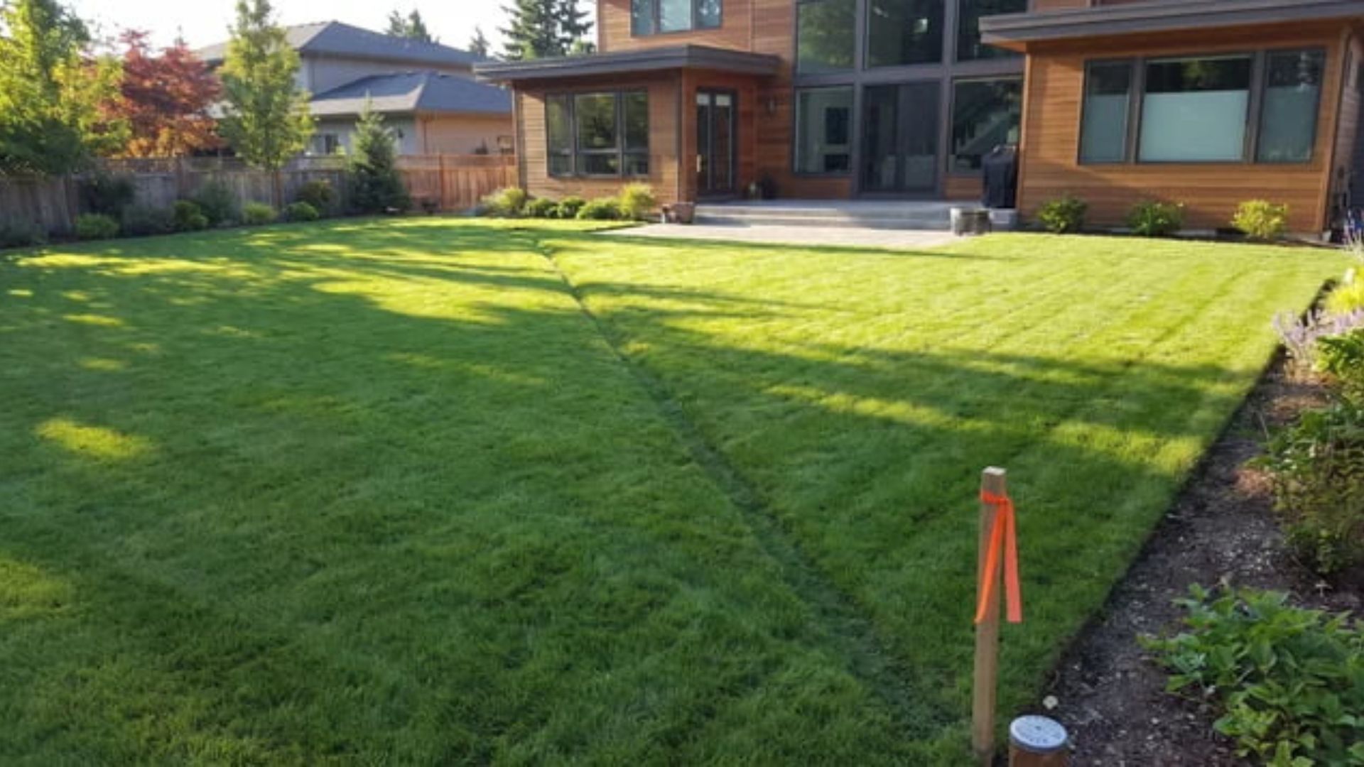 Backyard strip of grass over a drainage easement with a survey marker near the property boundary line.